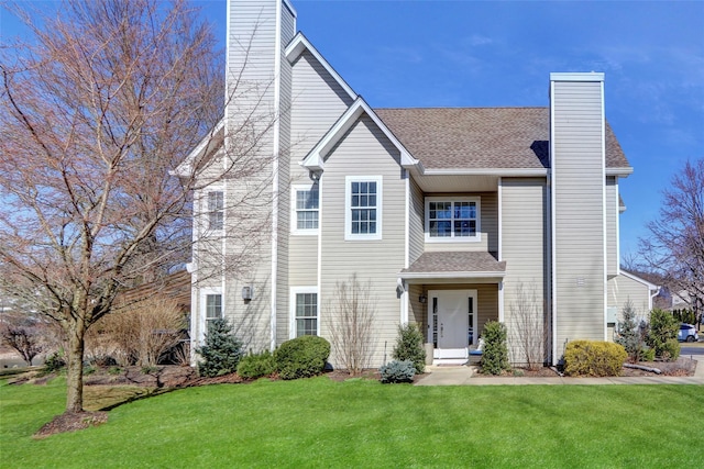 view of front of property with a front lawn, a chimney, and a shingled roof