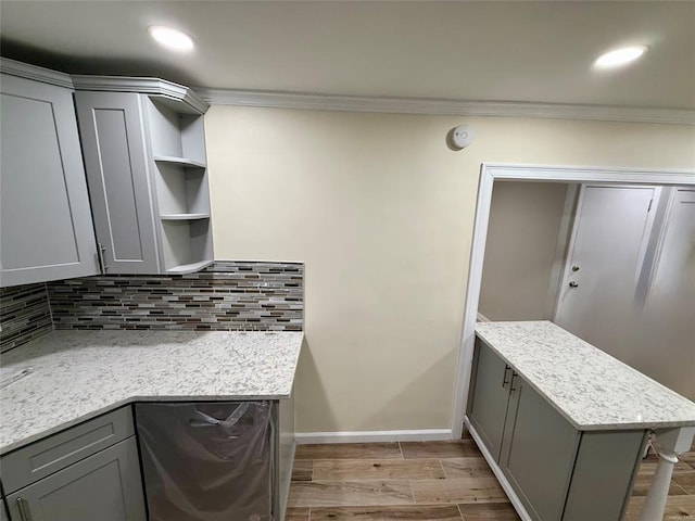 kitchen with gray cabinetry, crown molding, wood finish floors, decorative backsplash, and open shelves