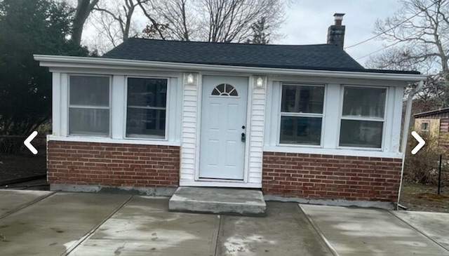 exterior space with brick siding, a chimney, and entry steps