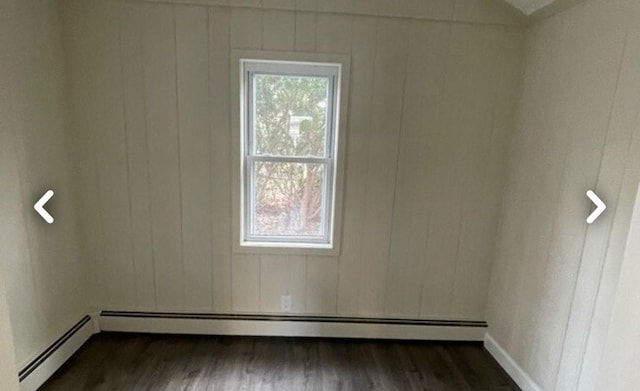 empty room featuring dark wood-type flooring and baseboard heating