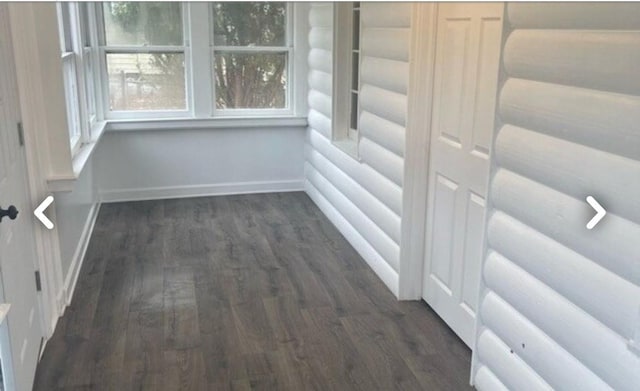 interior space featuring rustic walls, baseboards, and wood finished floors