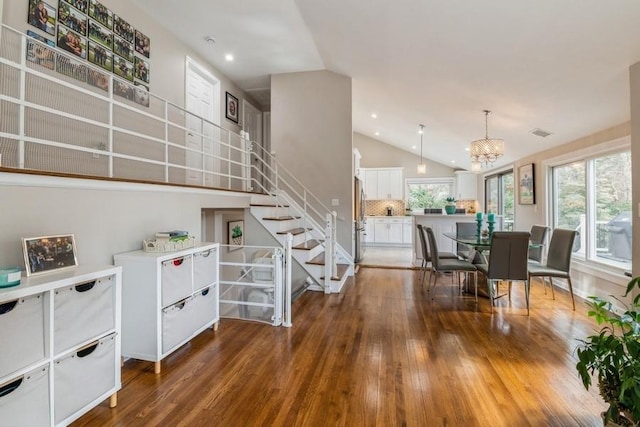 dining area with hardwood / wood-style floors, stairway, visible vents, lofted ceiling, and a notable chandelier