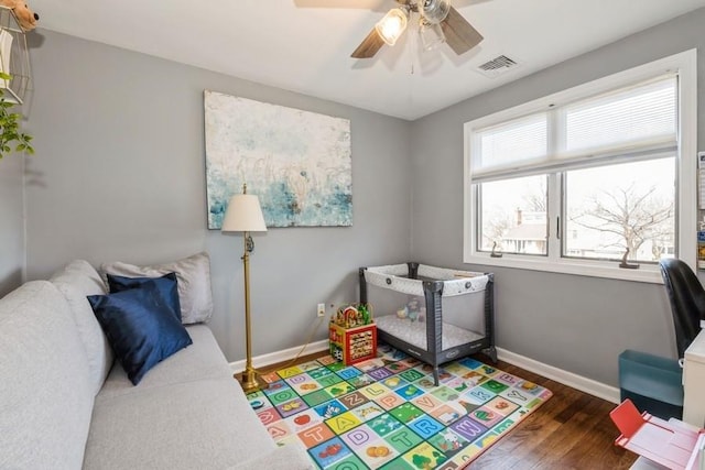 bedroom with ceiling fan, visible vents, baseboards, and wood finished floors