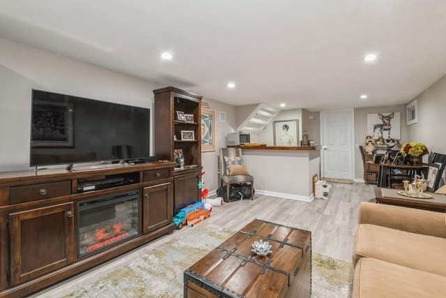 living area featuring stairs, recessed lighting, light wood-style floors, and a fireplace