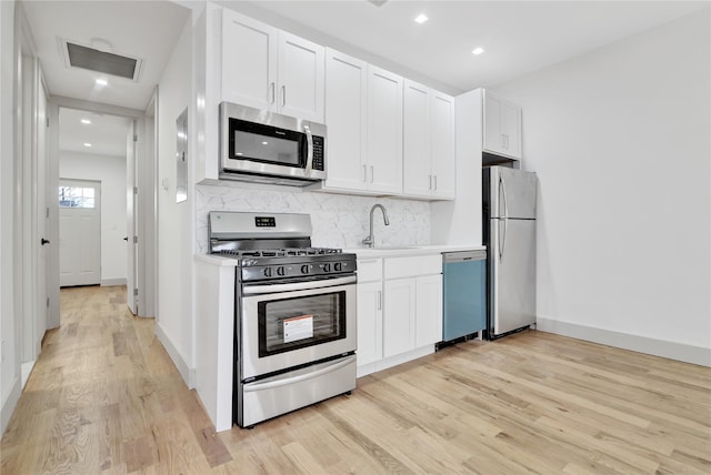 kitchen featuring tasteful backsplash, visible vents, light wood finished floors, appliances with stainless steel finishes, and a sink