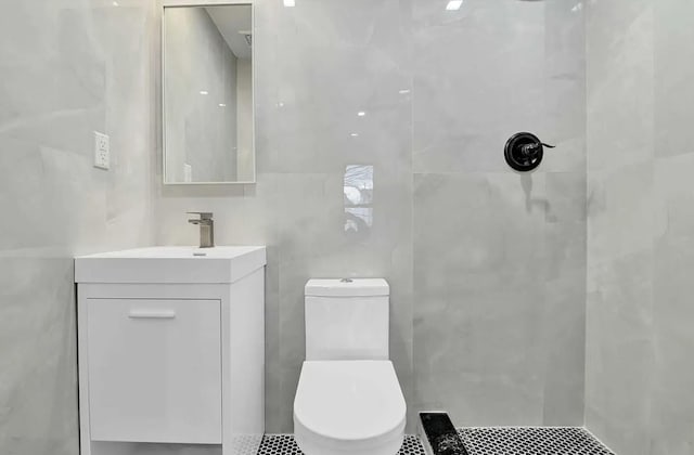 full bathroom with toilet, vanity, tiled shower, and tile walls