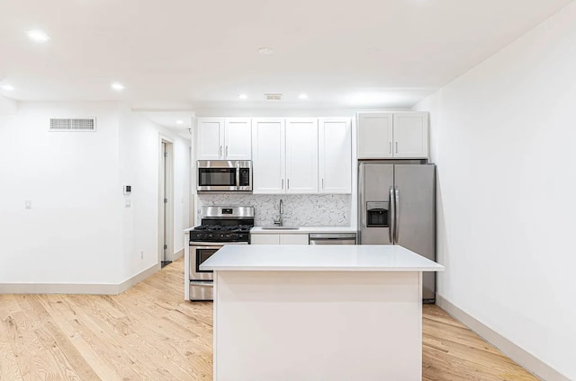 kitchen with light wood-type flooring, visible vents, a sink, tasteful backsplash, and stainless steel appliances