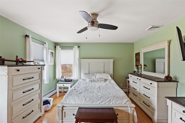 bedroom featuring visible vents, light wood-type flooring, baseboard heating, a ceiling fan, and a baseboard radiator