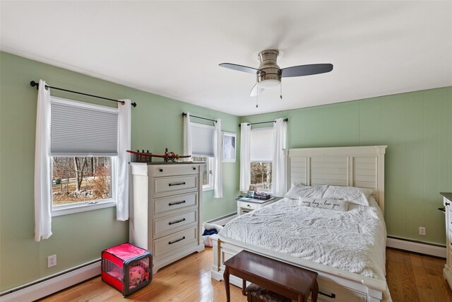 bedroom with ceiling fan, a baseboard radiator, and light wood-style flooring