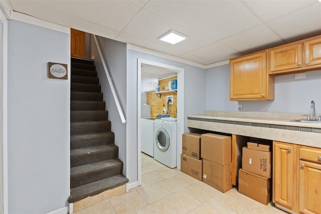 clothes washing area featuring washer and dryer, light tile patterned flooring, laundry area, and a sink