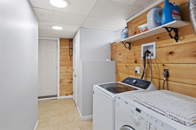 clothes washing area featuring laundry area, washer and dryer, and wood walls