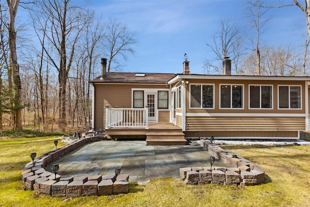 back of property with a patio area, a lawn, a chimney, and a deck