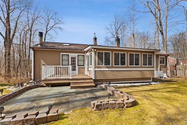 back of property with a patio, a yard, a chimney, and a wooden deck