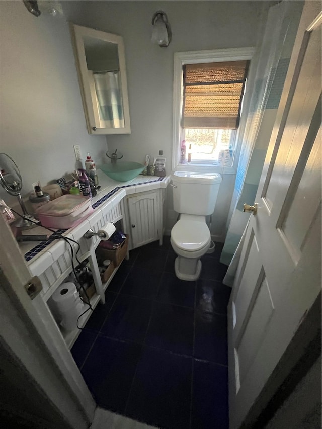 half bathroom featuring toilet, vanity, and tile patterned flooring