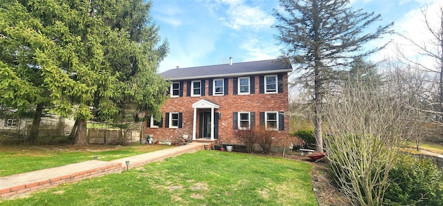 colonial home with brick siding, a front yard, and fence