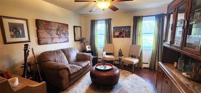 sitting room featuring a baseboard radiator, a ceiling fan, wood finished floors, and a textured ceiling