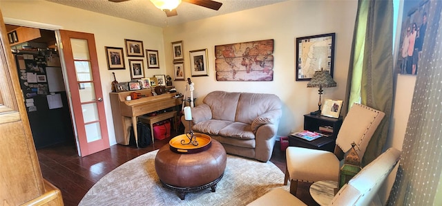 living room featuring a textured ceiling, a ceiling fan, and dark wood-style floors