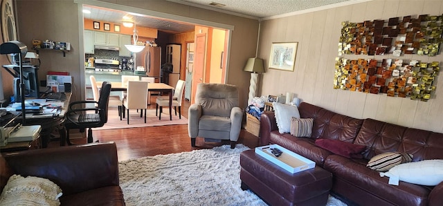 living room with wood walls, ornamental molding, and wood finished floors