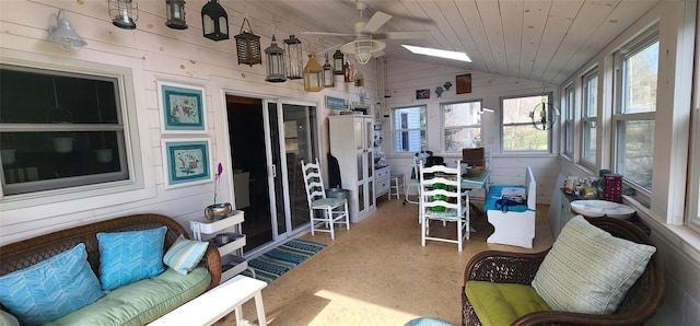 sunroom with lofted ceiling, a ceiling fan, wood walls, and wood ceiling