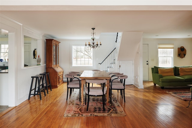 dining space with stairs, plenty of natural light, light wood-style flooring, and crown molding