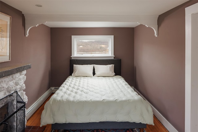 26 Curry Ln, Hyde Park, NY 12538 - bedroom featuring a stone fireplace, wood finished floors, baseboard heating, and baseboards