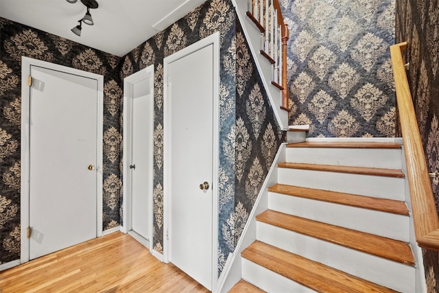 stairway featuring wallpapered walls and wood finished floors