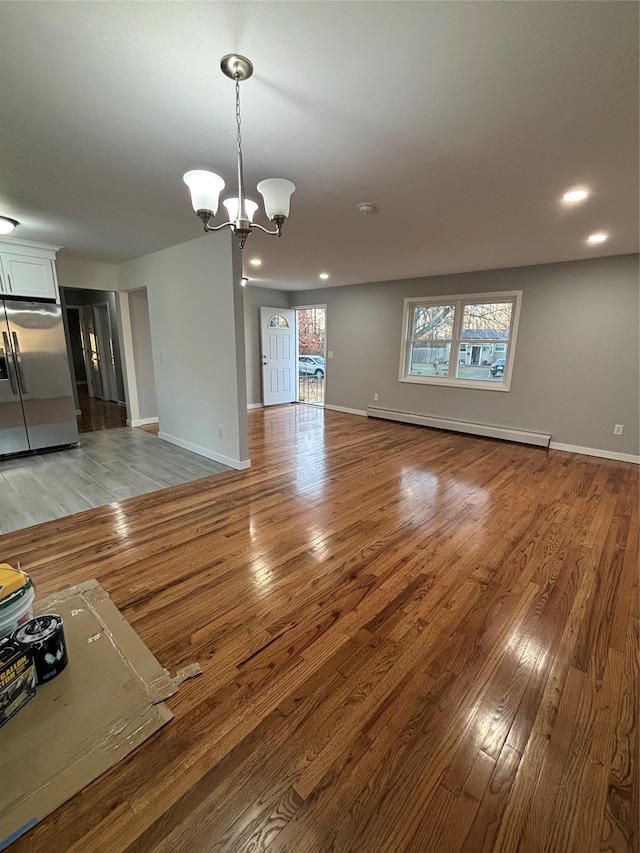 unfurnished living room featuring light wood-type flooring, a notable chandelier, recessed lighting, a baseboard radiator, and baseboards