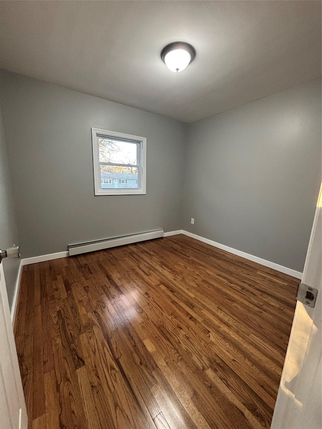 unfurnished room with dark wood-type flooring, baseboards, and a baseboard radiator