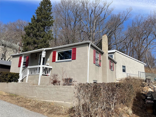 view of front of home featuring stucco siding, a porch, and a chimney