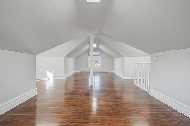 bonus room featuring a wall mounted air conditioner, baseboard heating, wood finished floors, and vaulted ceiling