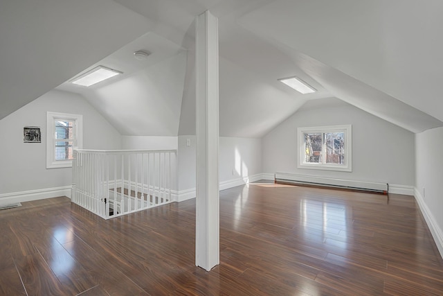 additional living space featuring a baseboard heating unit, baseboards, visible vents, and wood finished floors