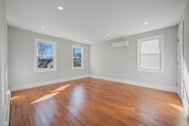 empty room with recessed lighting, baseboards, wood-type flooring, and an AC wall unit