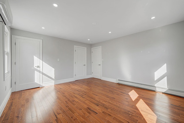 unfurnished room featuring recessed lighting, a wall mounted air conditioner, baseboards, and hardwood / wood-style floors