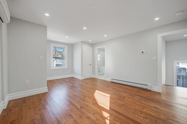 unfurnished living room with hardwood / wood-style floors, baseboards, recessed lighting, a wall mounted air conditioner, and baseboard heating