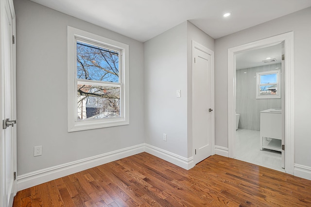 interior space with recessed lighting, wood finished floors, baseboards, and connected bathroom