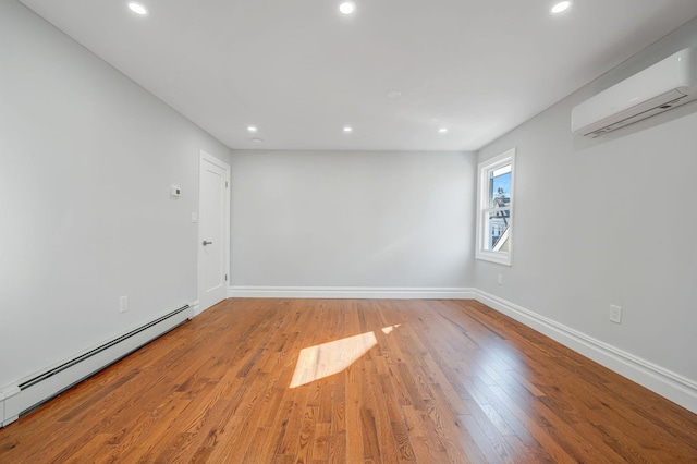 empty room featuring baseboards, recessed lighting, wood-type flooring, a wall mounted air conditioner, and a baseboard heating unit