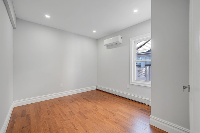 spare room featuring a wall unit AC, baseboards, recessed lighting, hardwood / wood-style flooring, and baseboard heating