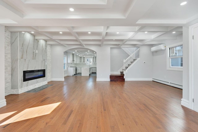 unfurnished living room featuring an AC wall unit, a baseboard heating unit, coffered ceiling, stairway, and a premium fireplace