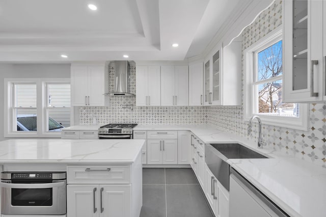 kitchen featuring stainless steel appliances, white cabinetry, dark tile patterned floors, and wall chimney range hood