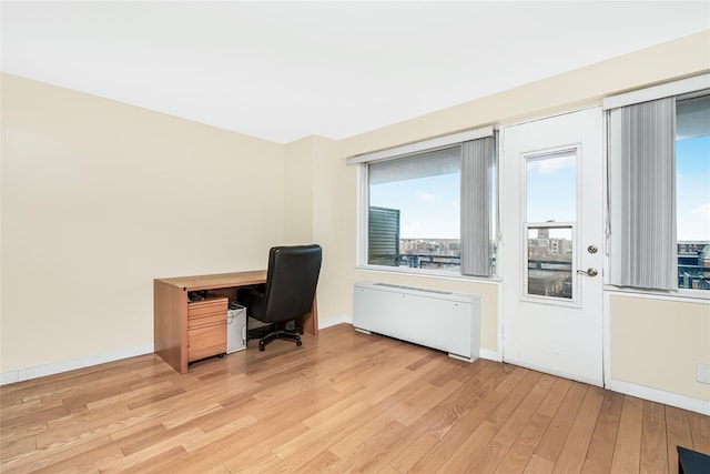 office space with light wood-type flooring, baseboards, and radiator