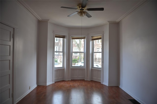 empty room featuring ceiling fan, wood finished floors, visible vents, and ornamental molding