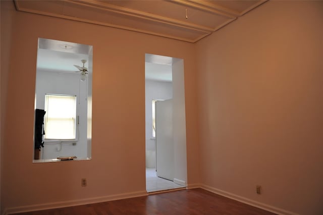 unfurnished room featuring ceiling fan, baseboards, attic access, and wood finished floors