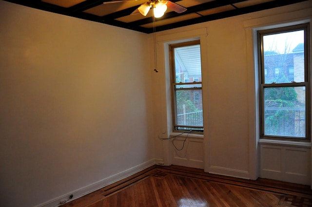 spare room with dark wood-type flooring, a ceiling fan, and baseboards