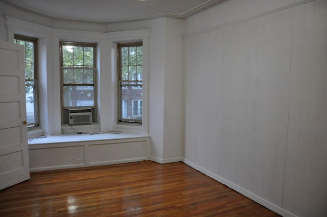 empty room with cooling unit, baseboards, and dark wood-style flooring