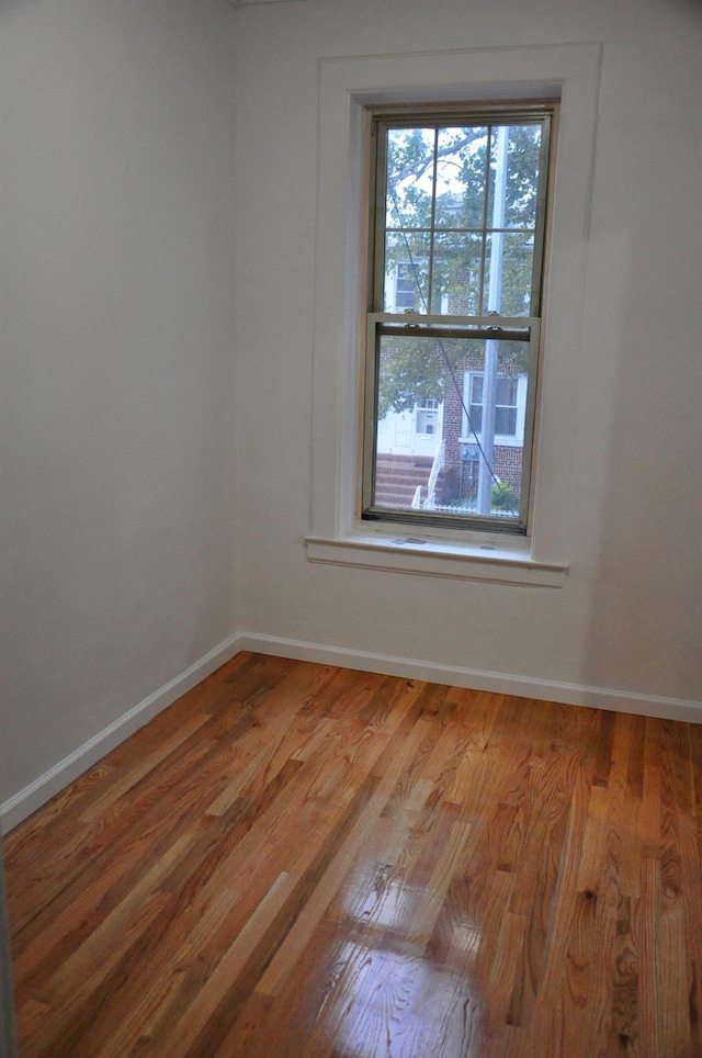 spare room with baseboards and wood finished floors