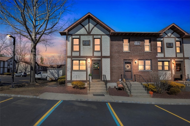 view of front of house featuring stucco siding, brick siding, and uncovered parking