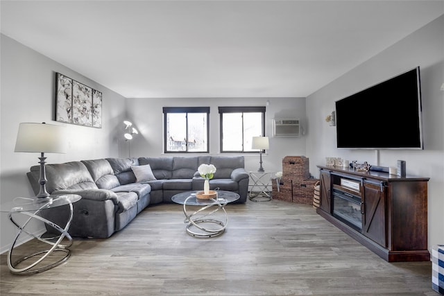 living area with an AC wall unit and wood finished floors