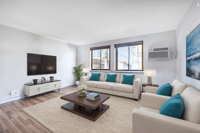 living area with baseboards, a wall unit AC, and wood finished floors