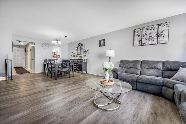 living area with a chandelier, baseboards, and wood finished floors