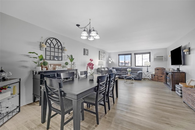 dining space with a chandelier, an AC wall unit, and light wood-style floors